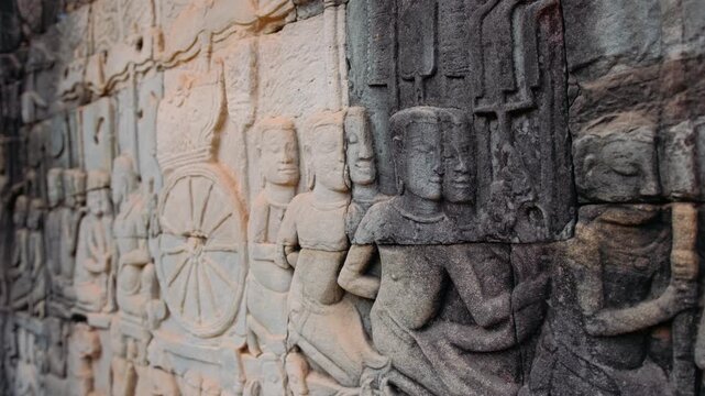 Detailed stone bas relief carvings depicting historical and mythological scenes on the ancient walls of the bayon temple in Cambodia, Siem Reap. Archeology concept.