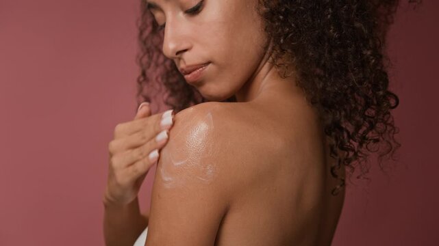 Close up of brunette young woman applying aromatic body butter on skin as part of skincare