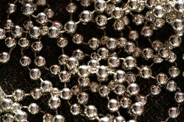 Macro silver bead garland with glossy reflections; selective focus and soft blur create a luxe holiday background and sparkling Christmas elements for happy new year packaging or cards.
