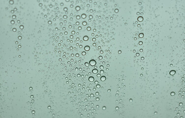 big raindrops, little raindrops, and medium raindrops. collected on the outside of a vehicle window creating unique designs and unique trails through the droplets