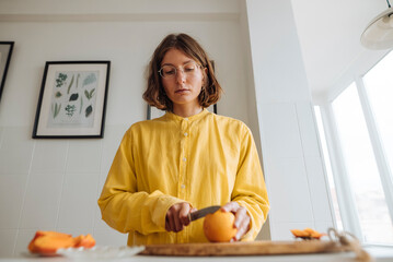 Home cook slicing oranges on wooden surface during morning routine