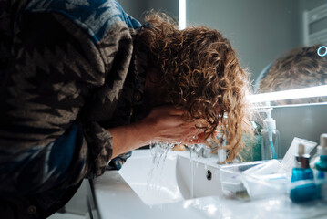 Actor calmly removes makeup and revitalizes skin beside illuminated mirror