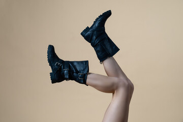 naked female legs in high boots raised up on a yellow background