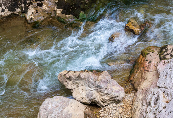 a mountain river with a rapid flow and an unusual stone bed and waterfalls in the summer