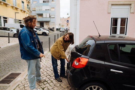 white man and white woman inspecting rear bumper of parked car - Powered by Adobe