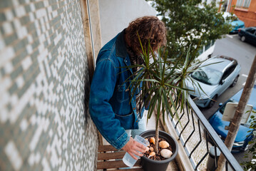 Fototapeta premium Man caring for plant with pastries in cozy balcony setting