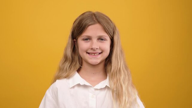 Charming little girl with long blonde hair and a gap-toothed smile looking at the camera. Beautiful kid expressing happiness and joy