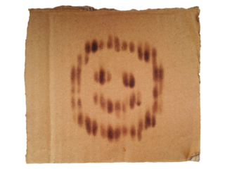 Burned smiley face icon on old corrugated cardboard texture isolated on transparent background