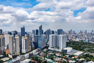 High-rise buildings in Makati with modern architecture, viewed under a partly cloudy sky on a bright day in Metro Manila