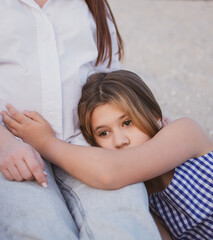 A teenage daughter rests her head on her pregnant mother's lap, hugging her belly for comfort and support in a quiet, tender moment of trust, togetherness and family love at home