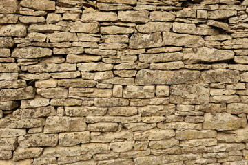 Rustic background made of weathered natural stone wall with unique irregular rock layers and rough surface details