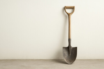 An old shovel stands against a light wall in the interior. Space for text.