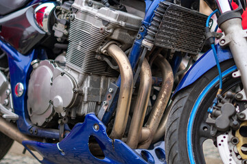 Motorcycle engine with air cooling and four exhaust headers photographed from the side next to the front wheel