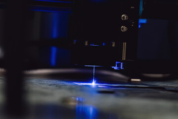 Close up of laser cutting paronite. Powerful blue laser burning complex gasket shape out of...