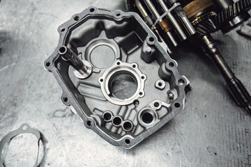 Disassembled old car gearbox with gears and tools on a workbench in an auto service garage. Repair, maintenance, and replacement of worn mechanical transmission parts in a vehicle.