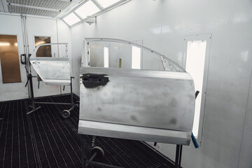 Parts of auto painting in chamber. Metal part of frame car. Auto spare parts. Painting car parts. Automotive paint services, quality auto body shop.