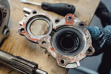 Disassembled old car gearbox with gears and tools on a workbench in an auto service garage. Repair, maintenance, and replacement of worn mechanical transmission parts in a vehicle.