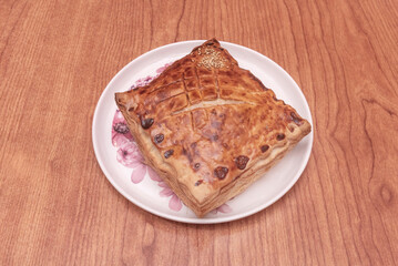 Apple tart in a puff pastry shell with thin slices of apple arranged in the shape of a rose, dusted with powdered sugar and served with a scoop of vanilla ice cream