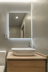 Modern bathroom with a floating walnut vanity unit, black brass faucet, and rectangular mirror with LED lighting