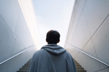 A man wearing a hoodie is walking up a set of stairs
