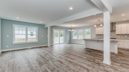 Unfurnished open concept living area featuring light blue walls, gray wood flooring, and modern kitchen space