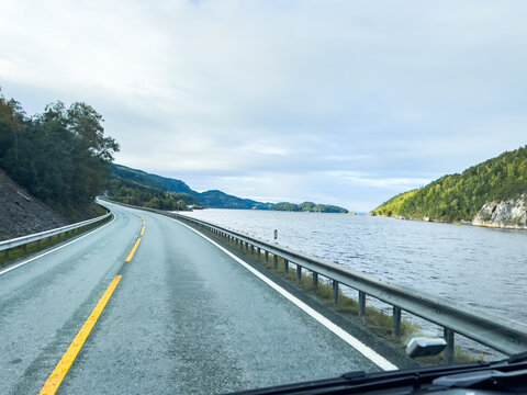 Scenic route stretching through colorful autumn landscape towards snow-capped mountain peak under clear blue sky - Powered by Adobe