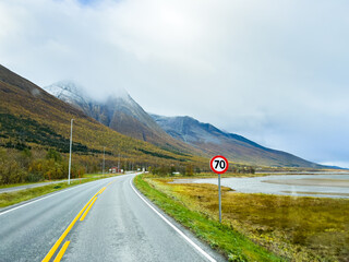 Fototapeta premium A motorhome parked by the road in the autumn landscape of Senja Island, Northern Norway, with fjords and mountains.