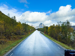 Naklejka premium A motorhome parked by the road in the autumn landscape of Senja Island, Northern Norway, with fjords and mountains.
