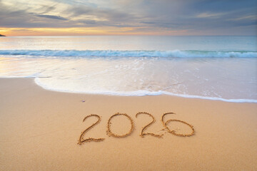 2026 year text symbol on the sea sand beach shore during sunset.