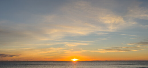 Obraz premium beach sunset, sun just above horizon on empty remote beach no people, colorful sky 