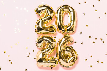 New year 2026 balloon celebration card. Gold foil helium balloons number 2026, party decoration, golden confetti stars on pink background. Flat lay, merry christmas banner, happy holidays concept.