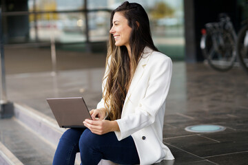 A young woman is working diligently on her laptop in a vibrant and modern urban setting