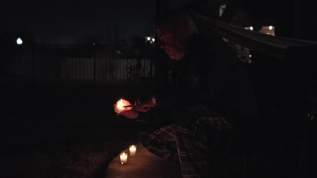 man lighting candles outdoors for colombian d&iacute;a de las velitas