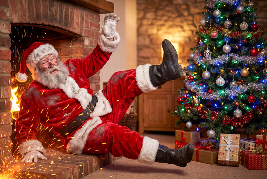 A sooty Santa Claus falls out of a brick fireplace with his legs and arms flailing dramatically next to a fully decorated and brightly lit Christmas tree surrounded by wrapped presents.
