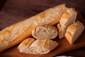 close-up of a freshly baked baguette and sliced bread pieces on a wooden board, showcasing airy texture and golden crust against a warm, cozy background, pastry, oven, bowl, meal, snack, dining