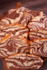 close-up view of deliciously sliced marble loaf cake with chocolate and vanilla swirls on a wooden cutting board in a warm, rustic setting, flavorful, aromatic, culinary, tasty, indulge, eat, serve