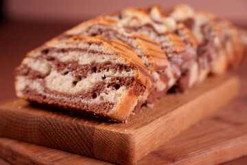 close-up of marbled loaf cake with swirled chocolate and vanilla layers displayed on wooden cutting board in a warm, cozy setting, highlighting texture and rich colors, decadent, fresh, indulgence