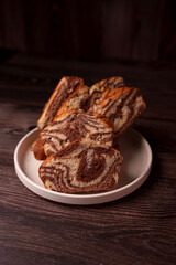 sliced marbled chocolate and vanilla cake on white plate set against rustic wooden table for a cozy dessert experience, culinary, kitchenware, homestyle, artisanal, gourmet, homebaked, nourishment