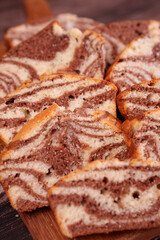 close-up of sliced marble cake displaying swirled chocolate and vanilla patterns on wooden board, emphasizing texture and warm tones, crumbly, soft, enticing, homestyle, savory, cozy, artistic