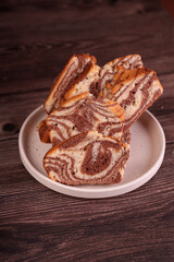 close-up of marble cake slices on rustic wooden table with soft natural lighting and earthy tones, highlighting swirled patterns and textures on white ceramic plate, inviting, cozy, styled, moist