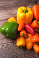vivid display of fresh colorful bell peppers on wooden surface highlighting green, yellow, orange, red hues illustrating vibrant healthy produce and rich textures, round, horizontal, shot, group
