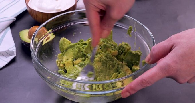 Ripe avocado being mashed in a glass bowl. Smooth food preparation process perfect for cooking tutorials, recipe videos, guacamole making, healthy eating content and kitchen demonstrations. 4k