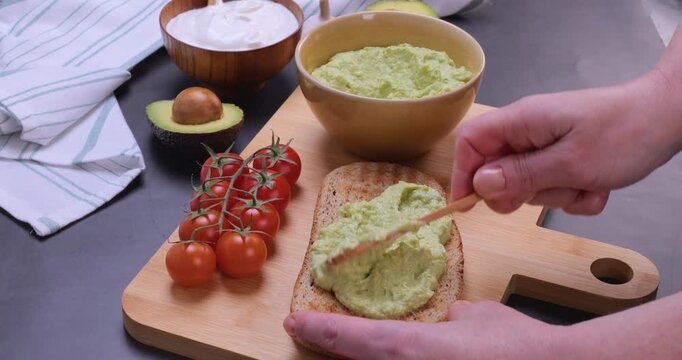 Creamy avocado being spread on a slice of bread. Smooth texture, natural food details make this clip ideal for healthy eating content, recipe videos, cooking tutorials and food advertising.