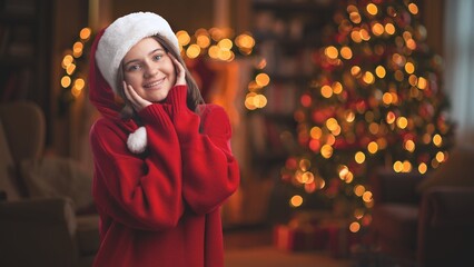 Beautiful santa girl in christmas hat on background