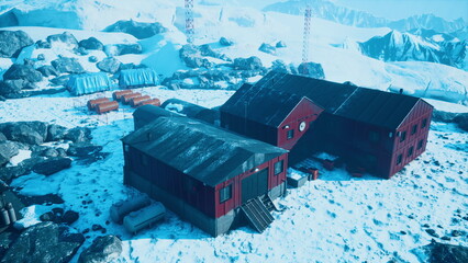 A red research station stands resilient against the harsh arctic landscape. Surrounded by snow and rocky terrain, scientists prepare for fieldwork amid towering mountains. © icetray