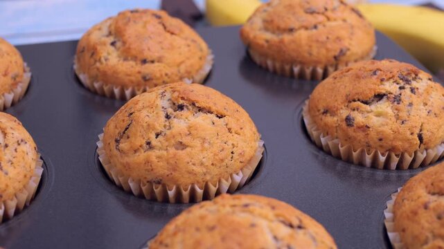 Freshly baked banana chocolate muffins taken out of the oven. Homemade, delicious and comforting dessert. Perfect for culinary projects, recipe videos, bakery promotions, food blogs, cooking content. 