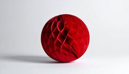 Red paper honeycomb ball decoration with symmetrical texture against plain white background
