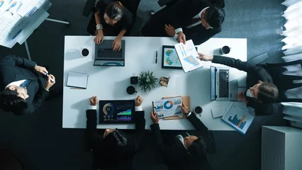 Fototapeten Pony Top down aerial view of manager standing and present marketing plan to skilled investor. Diverse business team working together to analyze financial statistic graph at meeting table. Directorate.  © InfiniteFlow