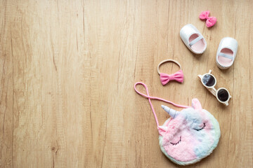 Flat lay of summer baby girl accessories - unicorn-shaped handbag and shoes, top view