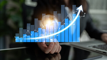 Visual representation of business growth, showcasing a person holding a light bulb while analyzing financial graphs and trends, symbolizing innovation and progress in strategy. Scalp